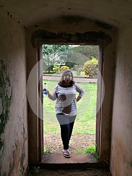 A young Indian woman posing at the entrance of a historic building.